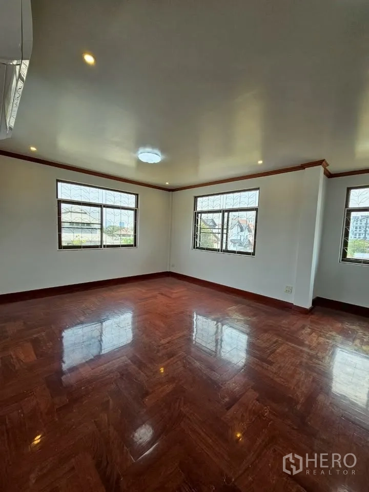 Home Office for rent in Wang Thonglang, Bangkok - Large corner room with multiple windows fitted with security grilles and shiny parquet floor.