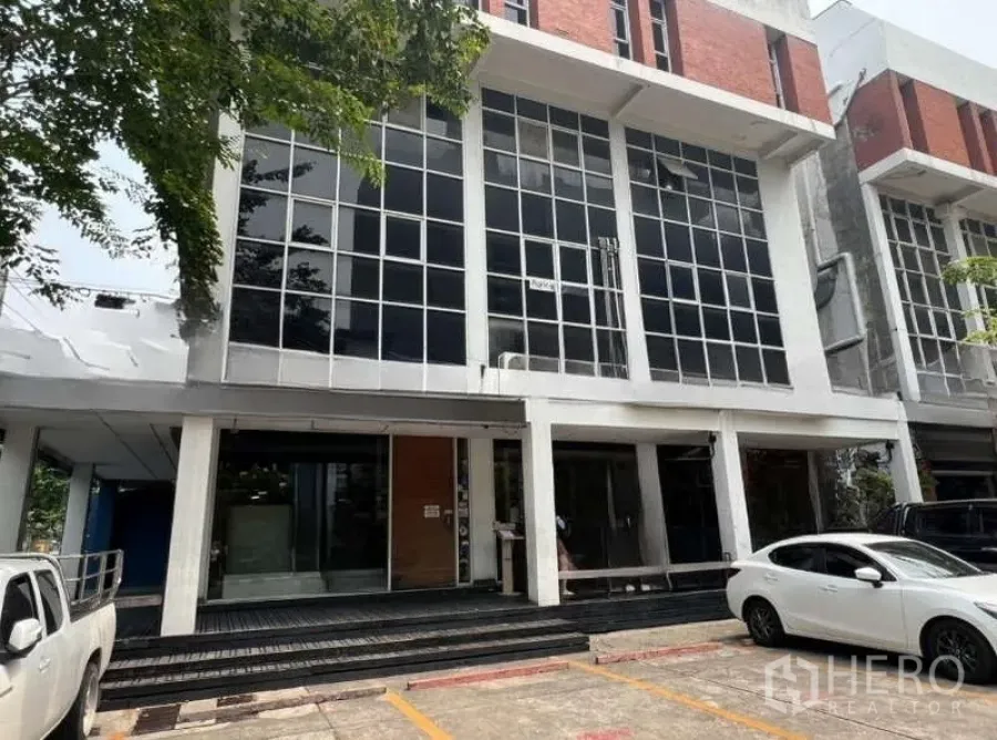 Shophouse for rent or sale in Khlong Toei, Bangkok - Street-level view of a modern Ekkamai shophouse with floor-to-ceiling glass facade and onsite parking.