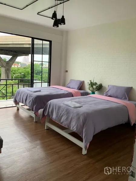 Home Office for rent or sale in Phra Khanong, Bangkok - Twin-bed room with balcony and views of an elevated rail structure.
