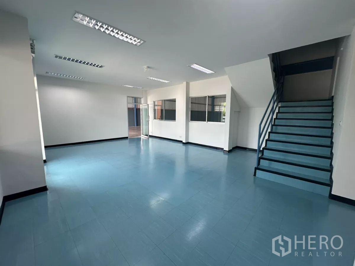 Factory for rent in Bang Phli, Samut Prakan - Spacious office area with staircase, glass entrance and blue flooring.