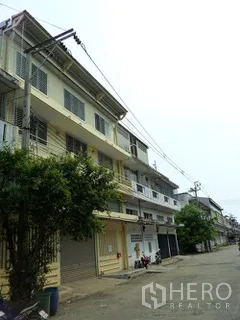 Factory for rent in Thung Khru, Bangkok - Row of multi-storey factory buildings along a quiet lane with shutters.