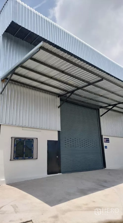 Warehouse for rent in Khlong Toei, Bangkok - Exterior of a new metal-clad warehouse with a large roller shutter and covered loading canopy.