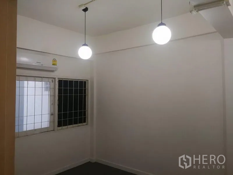 Townhouse for rent in Khlong Toei, Bangkok - Bedroom with two pendant lights, barred windows and a wall-mounted air conditioner