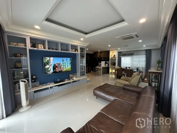 Detached House for rent in Lam Luk Ka, Pathum Thani - Bright lounge with blue media cabinetry, recessed ceiling and dining area.