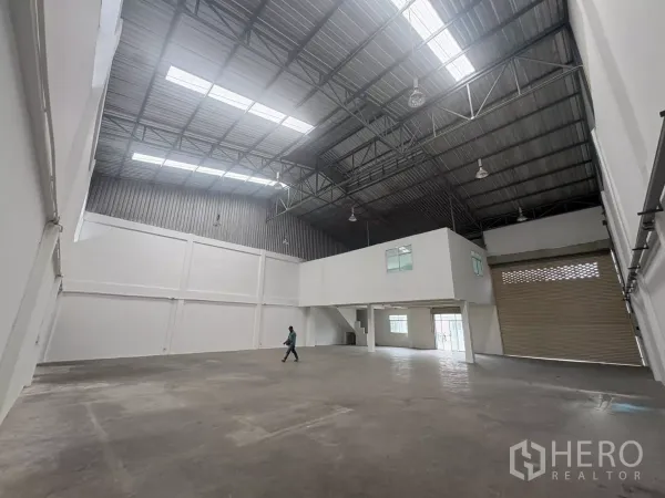 Factory for rent in Phra Samut Chedi, Samut Prakan - Open production floor with skylights, mezzanine structure and a loading roller shutter.