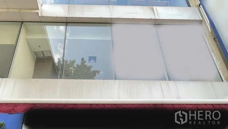 Retail Space for rent - Upper-floor retail facade with full-height glass windows and a red awning.