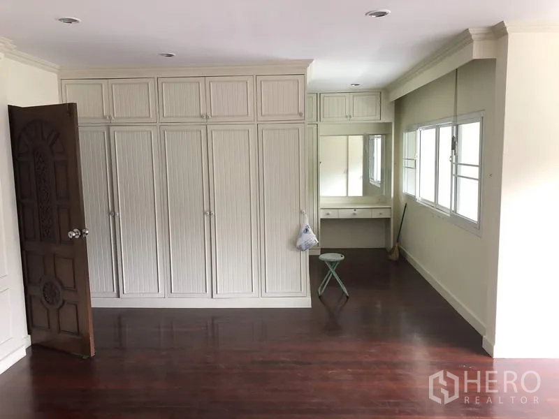Detached House for rent in Khan Na Yao, Bangkok - Bedroom featuring extensive built-in wardrobes, dressing table and polished wood flooring.