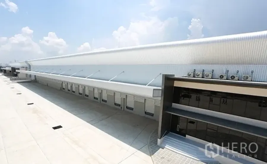 Warehouse for rent in Bang Pakong, Chachoengsao - Row of loading bays with roll-up doors, covered dock and wide concrete yard for trucks.