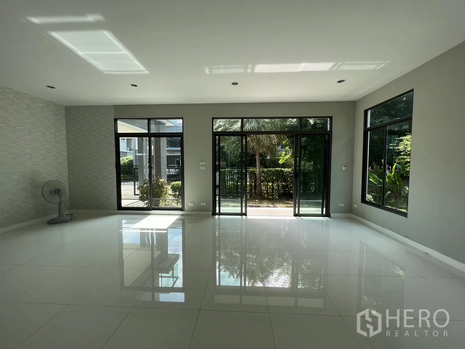 独立式住宅 出售在Suan Luang, Bangkok - 宽敞客厅，三扇推拉门通向露台与花园景观。