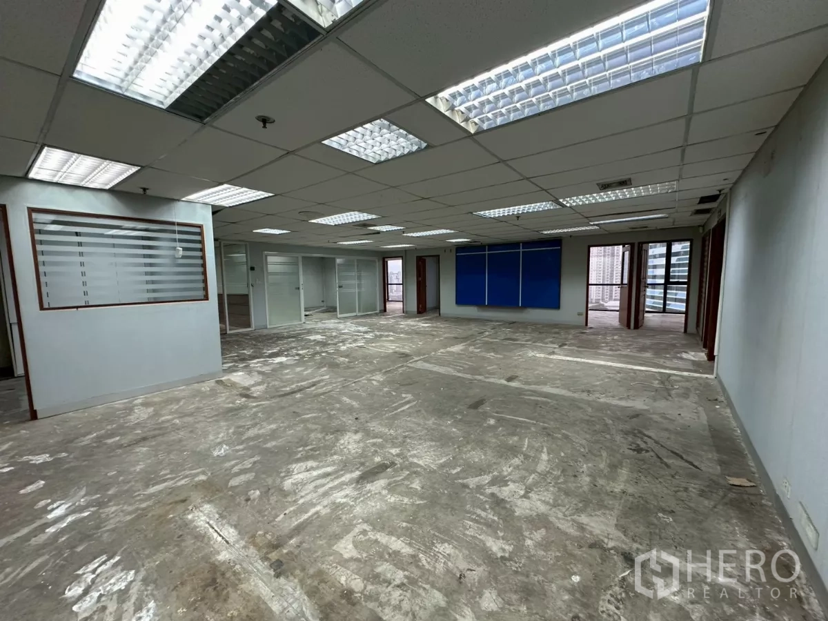 Office Space for rent in Khlong Toei, Bangkok - Wide office floor with multiple private rooms, fluorescent lighting and a blue notice board.