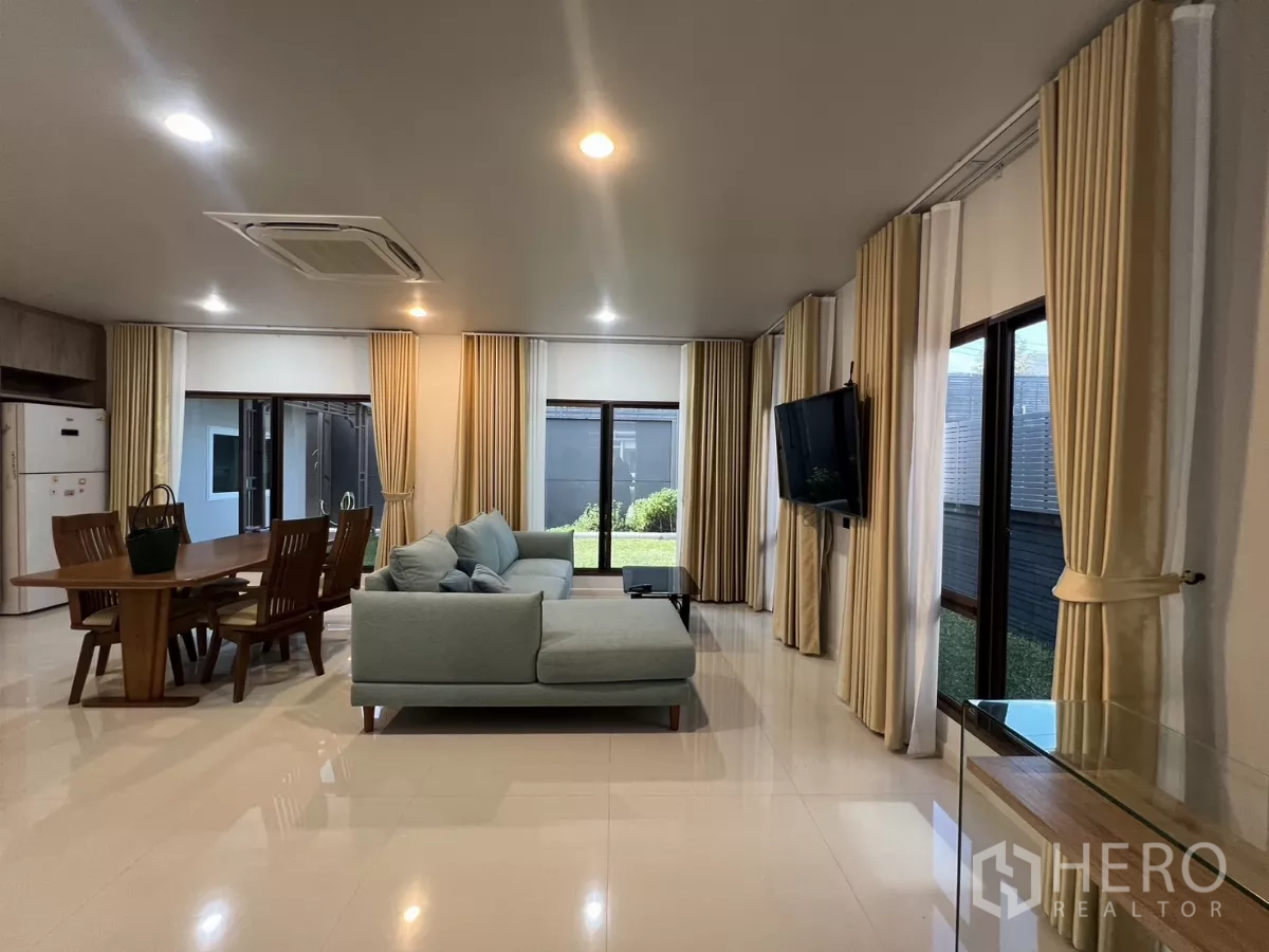 Detached House for rent or sale in Bang Kapi, Bangkok - Open-plan living and dining room with sofa set, wood table and large windows