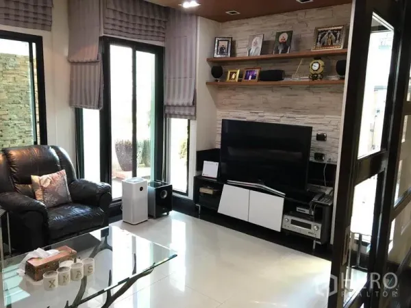 独立式住宅 出租在Khlong Toei, Bangkok - 电视起居角，皮质单椅、影音柜与壁架，落地窗采光。
