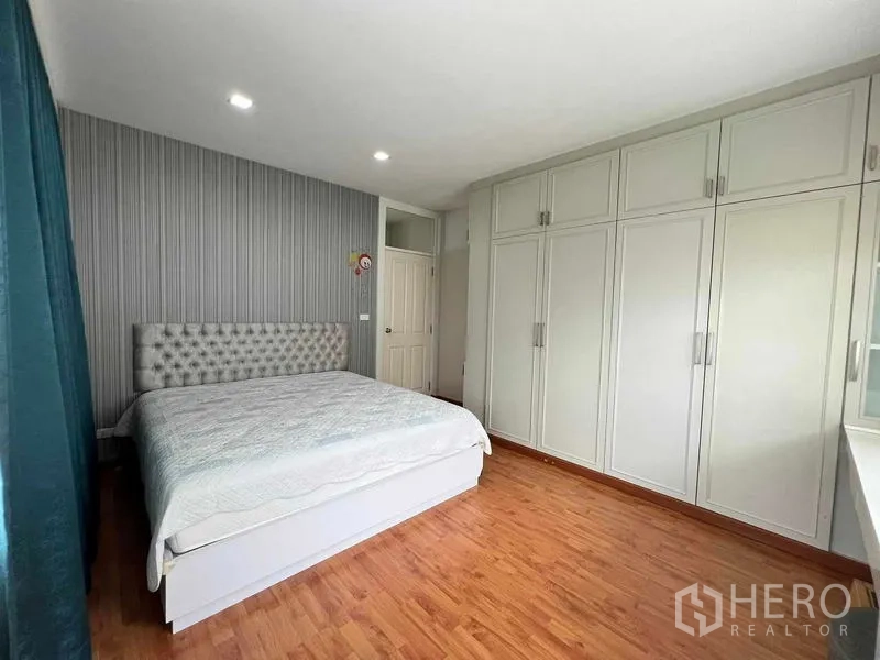 Detached House for sale in Bang Kruai, Nonthaburi - Master bedroom with large fitted wardrobes, king bed, wood flooring, and recessed lighting.