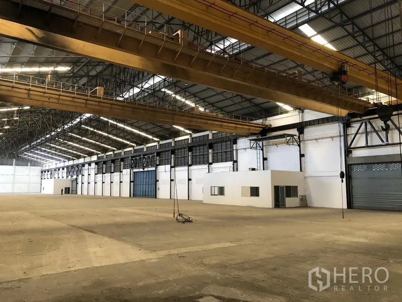 โรงงาน ให้เช่าในMueang Samut Prakan, Samut Prakan - มุมด้านข้างคลังสินค้า แสดงเครนเหนือศีรษะ ประตูม้วน และออฟฟิศ
