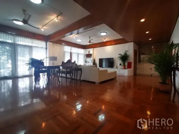 房间 出租在Khlong Toei, Bangkok - 开放式客餐厅，落地窗、电视墙与亮泽木地板。