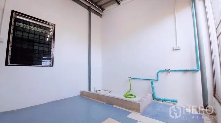 Townhouse for sale - Covered utility area with washing point and blue water pipes.