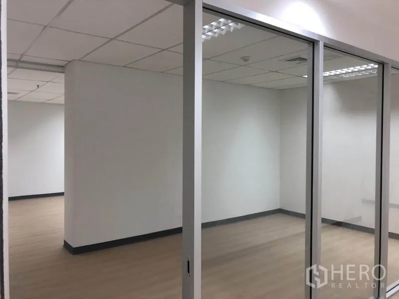 Office Space for rent in Watthana, Bangkok - Bright 53 sqm office in Watthana, Bangkok with a glass-partitioned meeting room, wood-look floors and suspended ceiling lights.