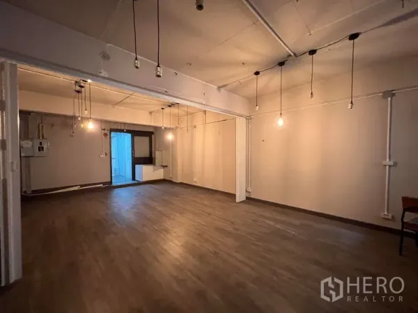 Shophouse for rent - Spacious upper floor room with hanging bulbs and wood-look flooring for flexible use.