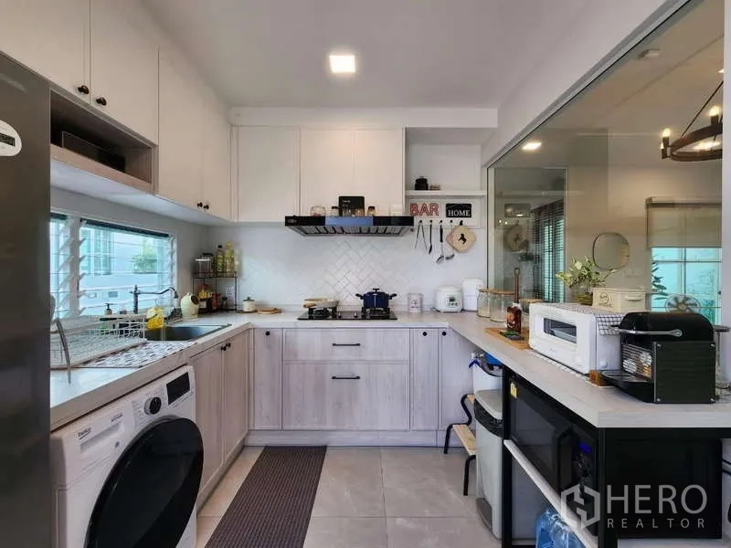 Detached House for rent or sale in Bang Phli, Samut Prakan - Modern L-shaped kitchen with gas hob, range hood and ample cabinetry.