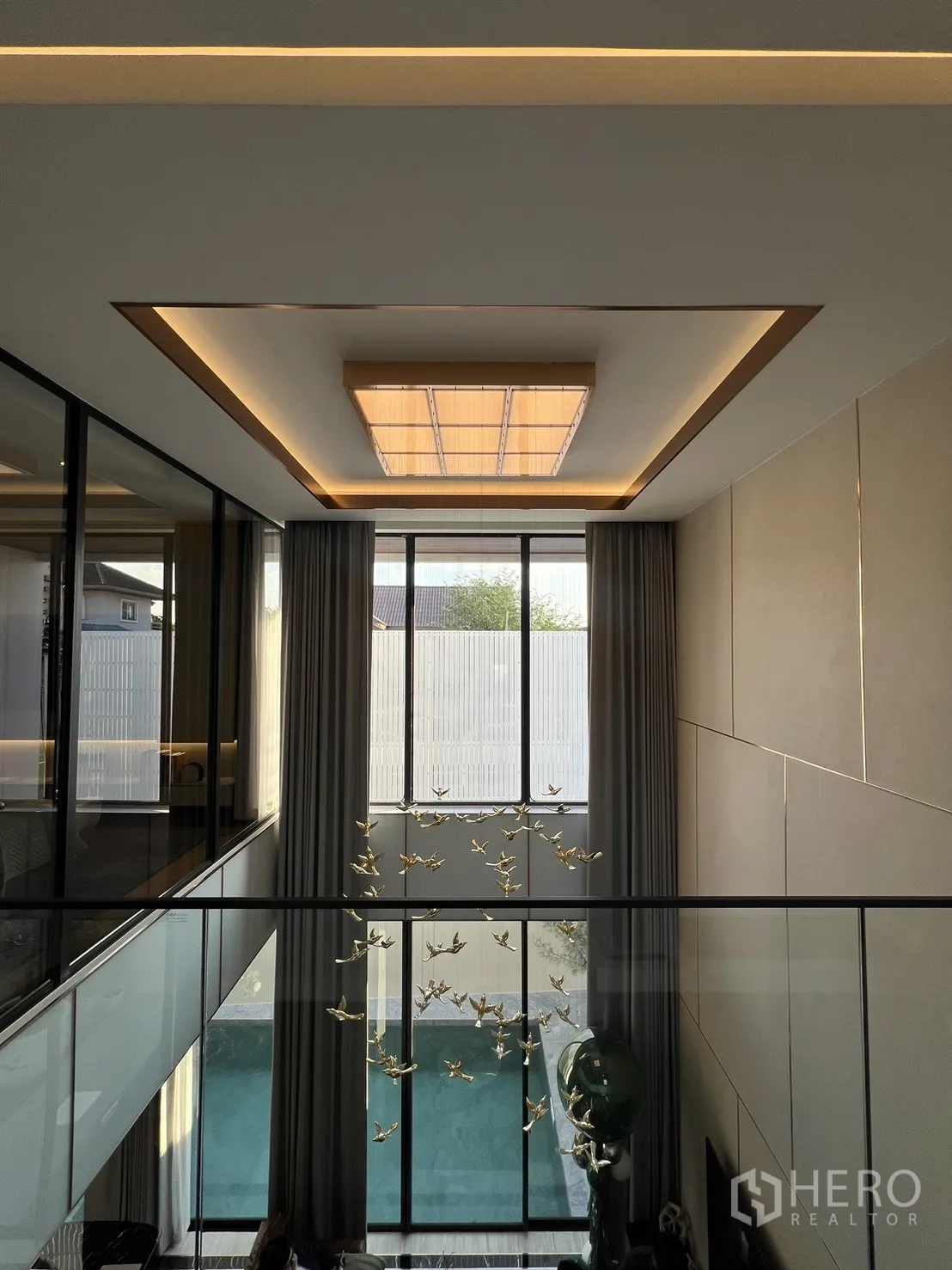 Detached House for sale in Lat Phrao, Bangkok - Mezzanine gallery overlooking the living room and pool through double-height glazing.