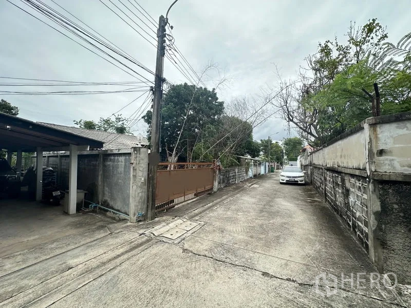地 出售在Phra Khanong, Bangkok - 地块旁宁静支路，路灯、围墙与绿植沿街分布。