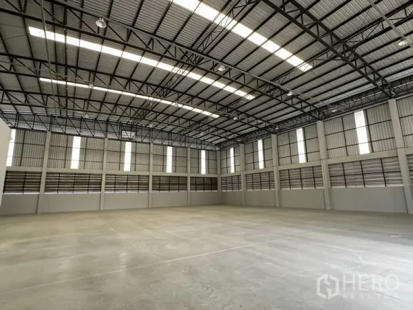 Warehouse for rent in Bang Phli, Samut Prakan - Spacious warehouse interior with high clear height, steel trusses, and polished concrete floor.