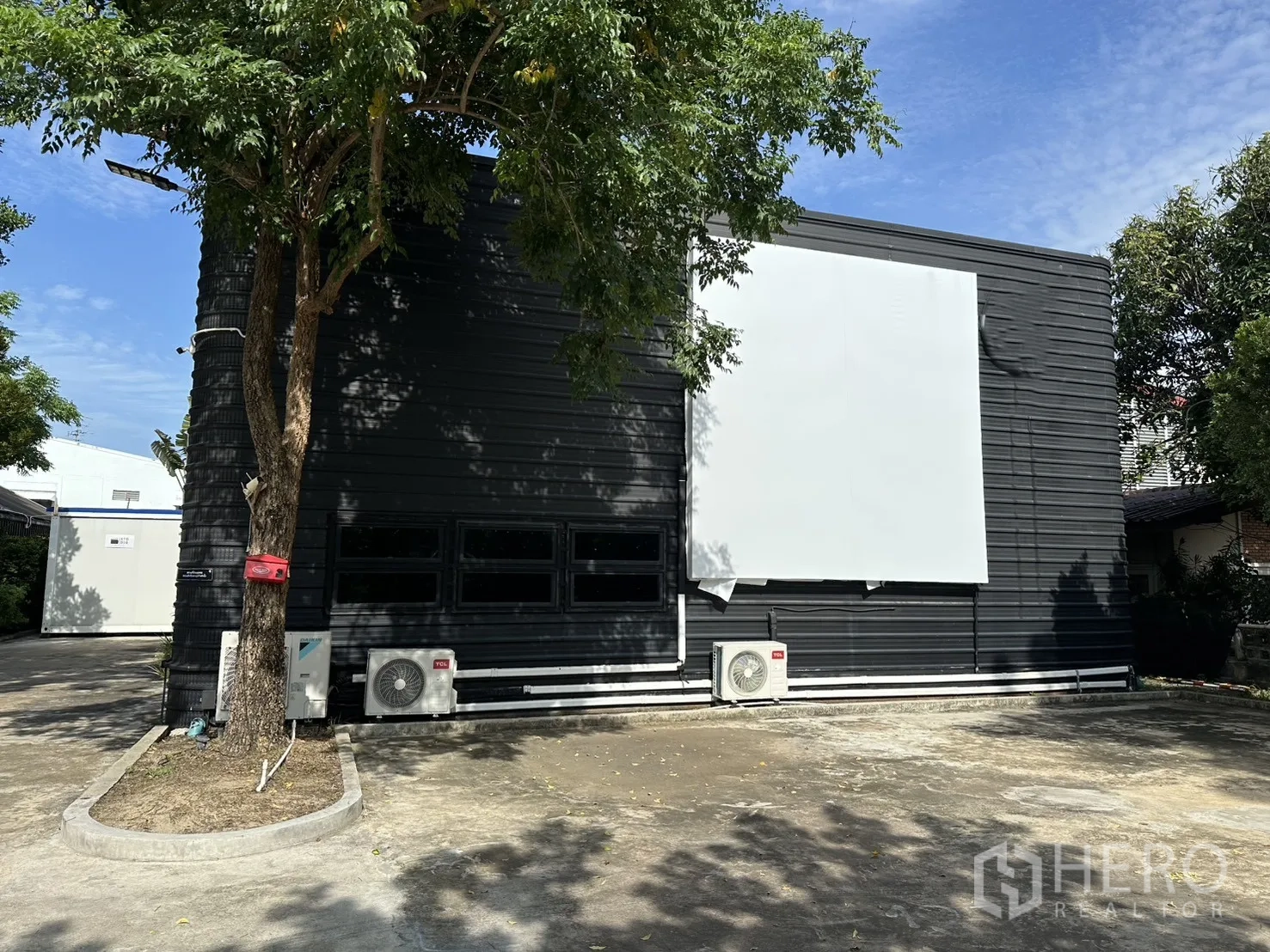Warehouse for rent in Phra Khanong, Bangkok - Close view of the warehouse facade with large signage panel and parking apron.