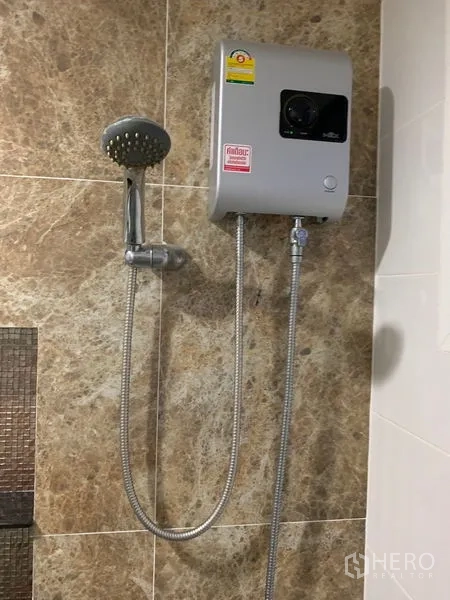 Detached House for sale in Prawet, Bangkok - Close-up of electric water heater and shower set on stone-look tiles.