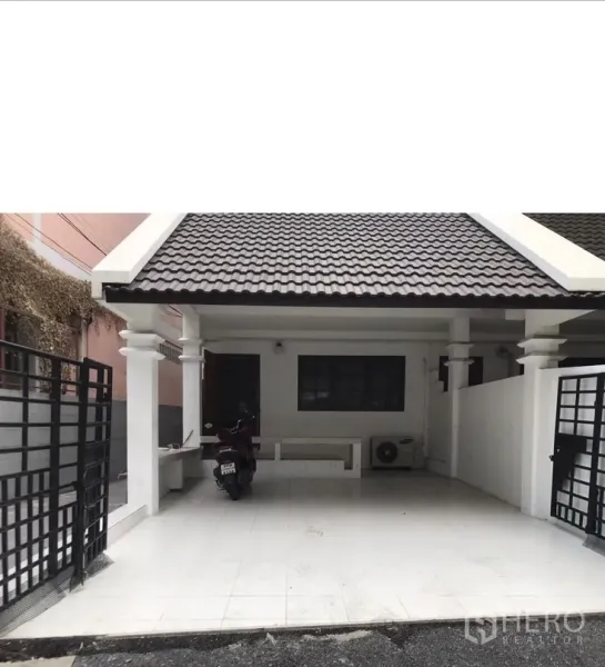 Townhouse for rent in Watthana, Bangkok - Close view of covered carport with white columns, black metal gate and tiled floor.
