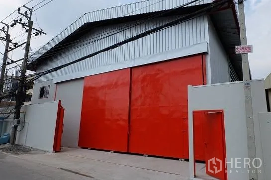 Warehouse for rent in Bang Phli, Samut Prakan - Side passage beside the warehouse with a partially opened sliding gate.