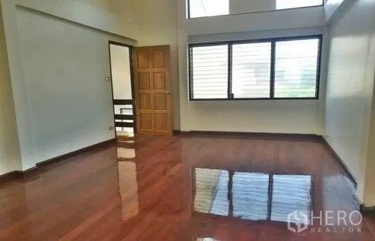 Home Office for rent in Chatuchak, Bangkok - Sunlit bedroom with polished wood flooring and wide windows.