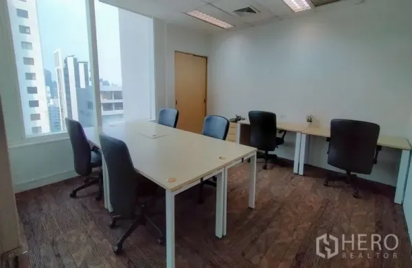 Office Space for rent in Khlong Toei, Bangkok - Corner office with four desks and natural light from tall windows overlooking Bangkok.