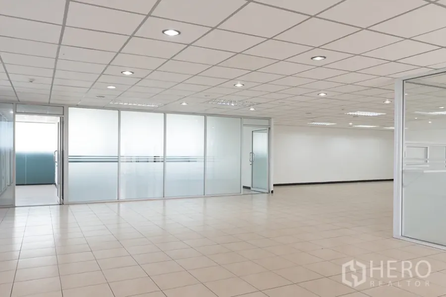 Office Space for rent in Din Daeng, Bangkok - Open‑plan office interior with beige tile flooring, recessed lighting, and frosted glass partitions creating meeting rooms.