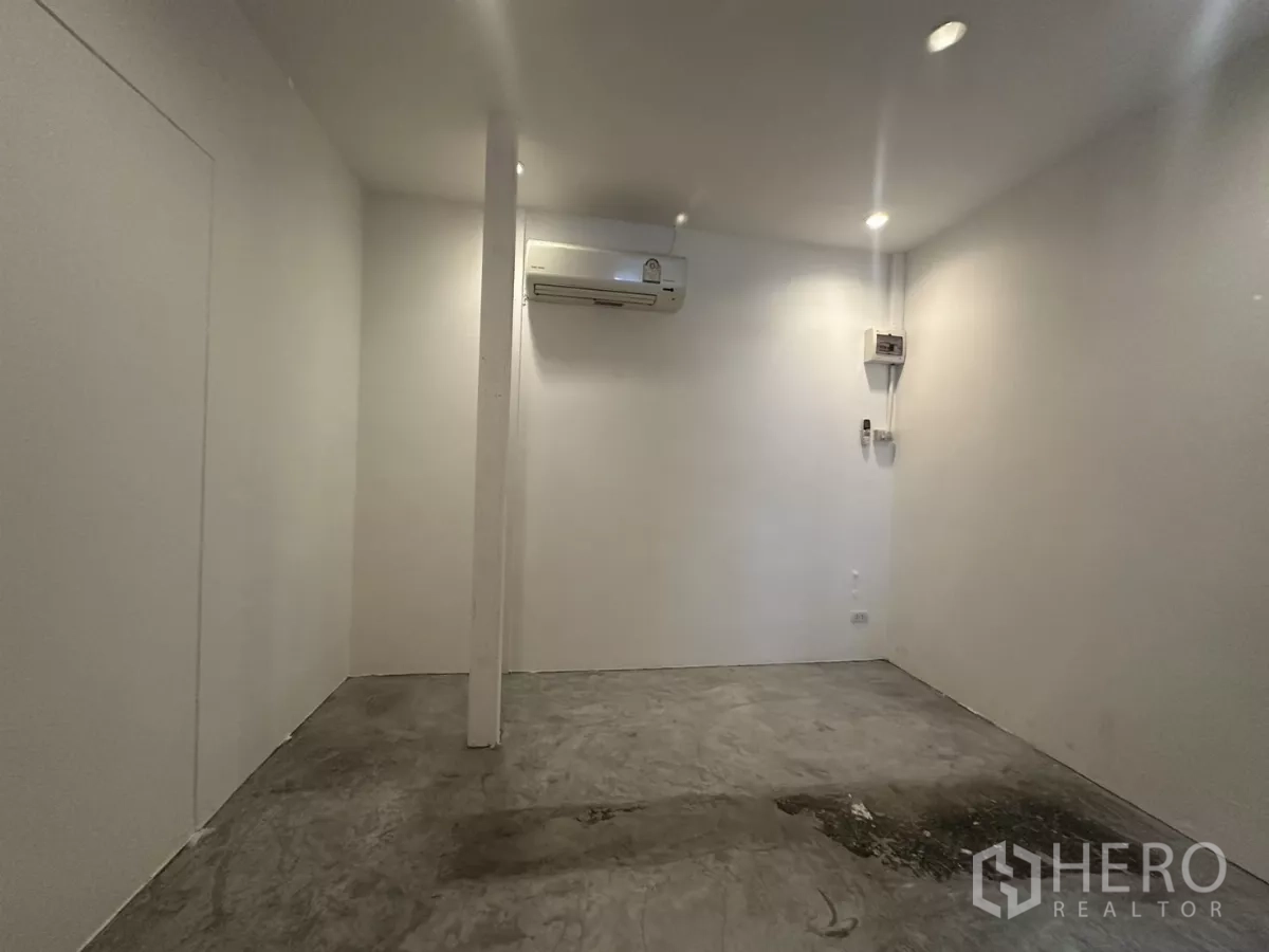 Retail Space for rent - Minimal retail space showing pillar, recessed ceiling lights, concrete floor and split-type air conditioner on the rear wall.