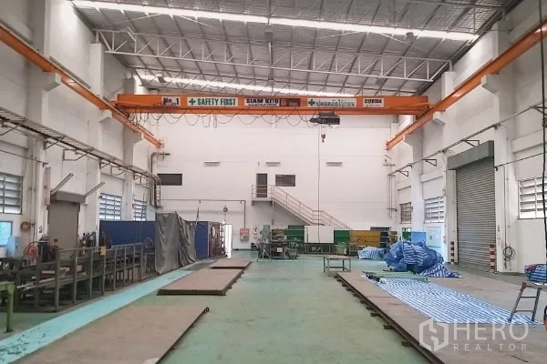Factory for sale in Rayong - High-bay production hall featuring an overhead crane, mezzanine, roller shutter and organized work areas.
