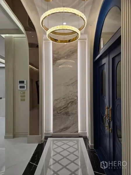 Detached House for rent or sale in Bang Kapi, Bangkok - Entry hall featuring arched blue double doors, marble wall panel and gold ring pendant lights.