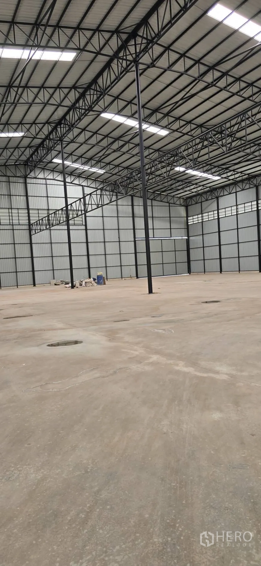 Factory for rent in Mueang Samut Sakhon, Samut Sakhon - Spacious warehouse interior with tall black steel trusses and expansive clear floor area.