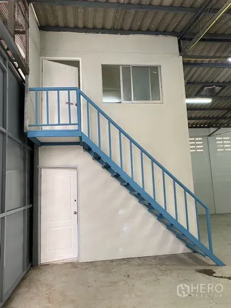 货栈 出租在Chatuchak, Bangkok - 仓内夹层办公室，配蓝色金属楼梯。