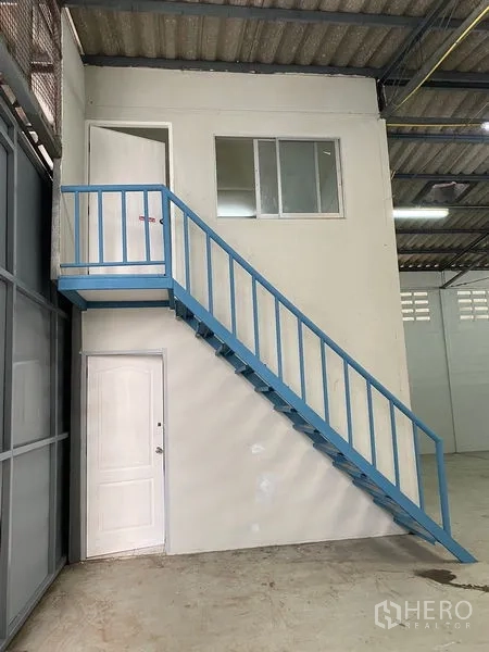 货栈 出租在Chatuchak, Bangkok - 仓内夹层办公室，配蓝色金属楼梯。
