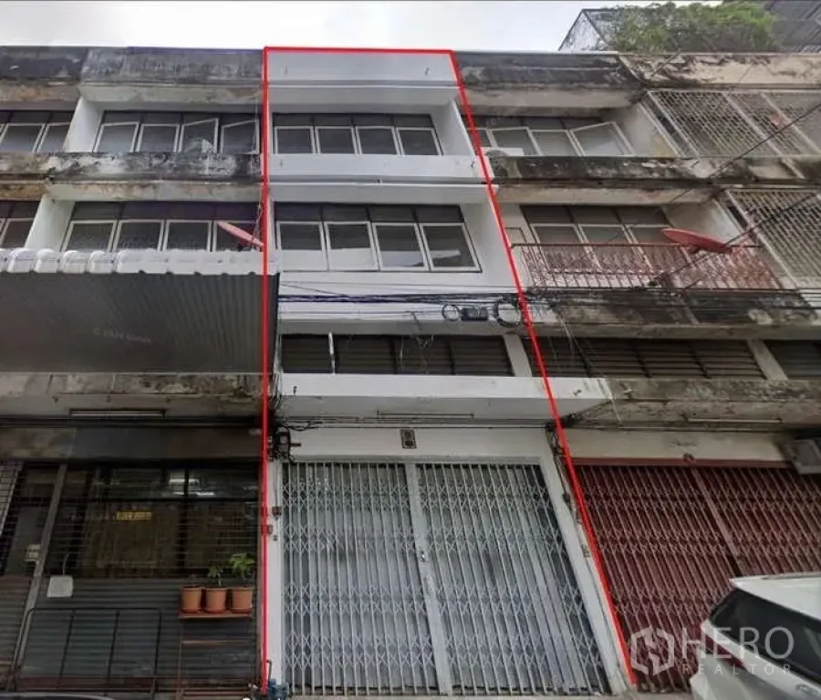 Shophouse for rent in Bang Na, Bangkok - Four-storey shophouse facade with metal folding gate and outlined unit.