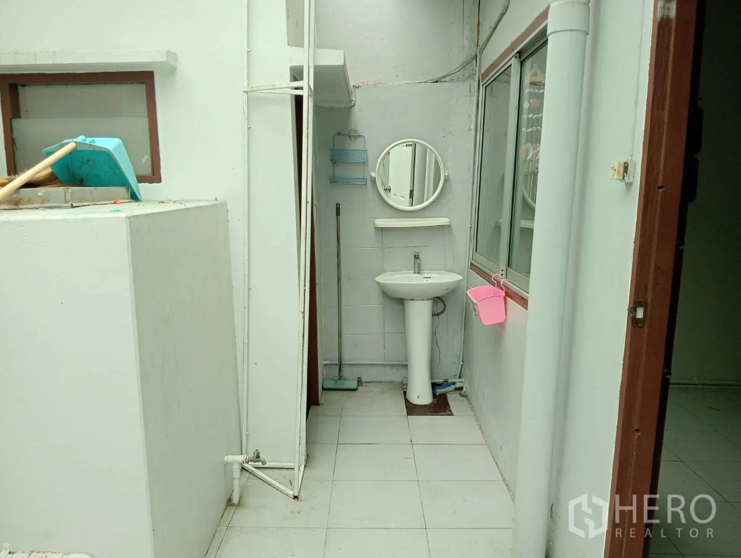 Home Office for rent in Khlong Toei, Bangkok - Rear utility area with pedestal sink, wall mirror and tiled floor.