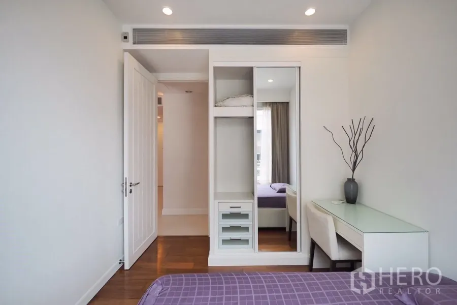 Condominium for rent in Pathum Wan, Bangkok - Bright bedroom with built-in mirrored wardrobe, glass-top desk, and purple bedding.