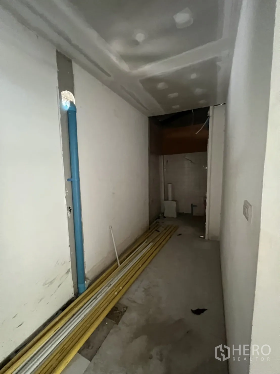 Shophouse for rent in Watthana, Bangkok - Narrow service corridor with exposed pipes and stacked construction materials.