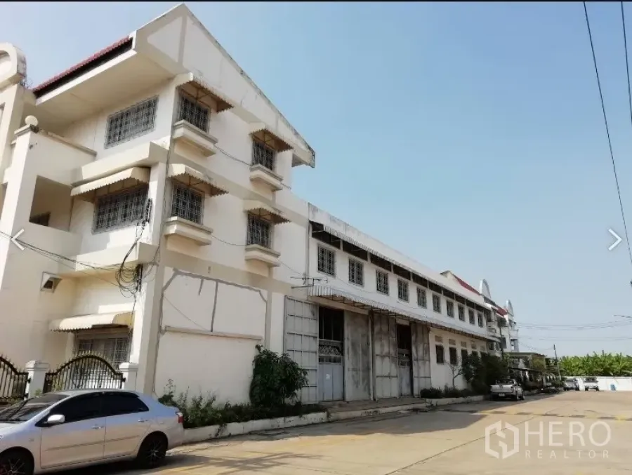 Warehouse for rent in Nakhon Pathom - Side elevation of the warehouse showing long façade, secure windows and ample road access.