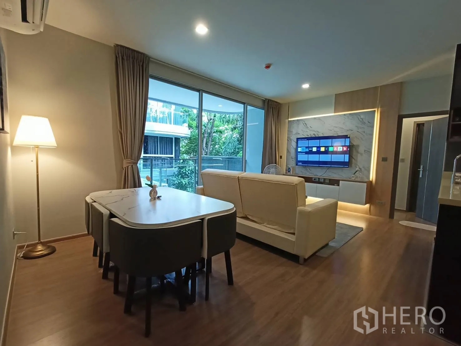 Condominium for rent in Watthana, Bangkok - Living and dining room with marble TV wall and large sliding doors to balcony.
