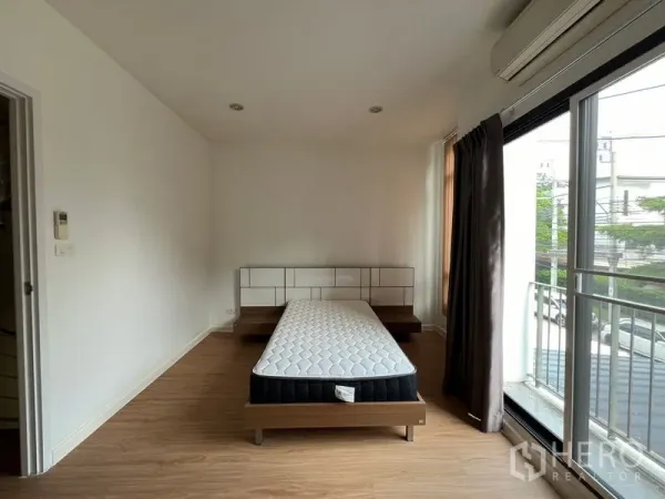 联排别墅 出租在Bang Kapi, Bangkok - 主卧带床，落地推拉门通向小阳台与空调。