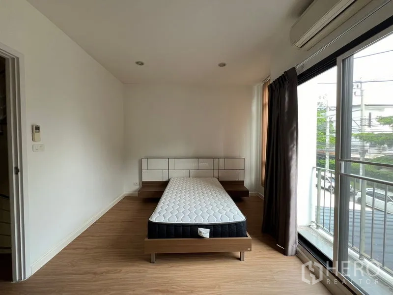 联排别墅 出租在Bang Kapi, Bangkok - 主卧带床，落地推拉门通向小阳台与空调。