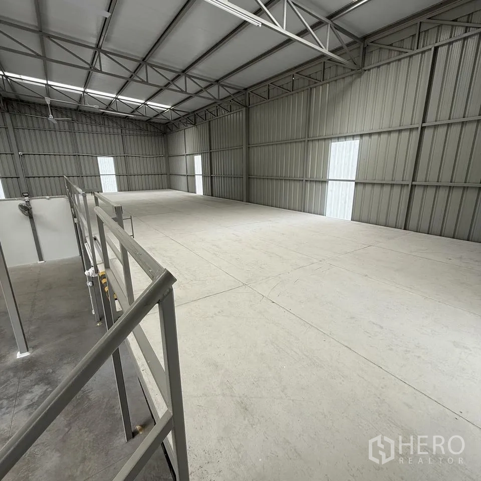Warehouse for rent or sale in Khlong Luang, Pathum Thani - Empty mezzanine storage deck with safety railings and overhead lighting.