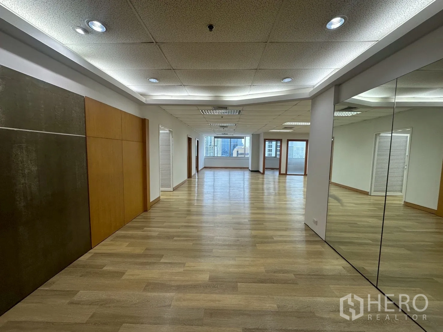 Office Space for rent - Spacious renovated office with wood floors, mirrored wall, and city-view windows.