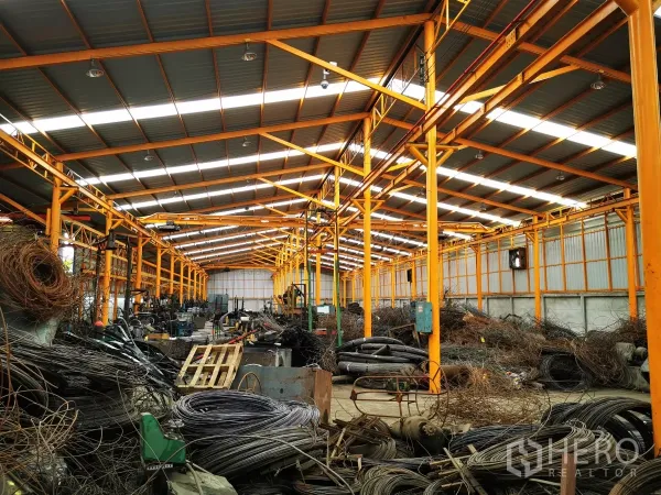 工厂 出售在Bang Bua Thong, Nonthaburi - 工厂内部空间开阔，橙色钢柱、采光带和多条行车轨道。